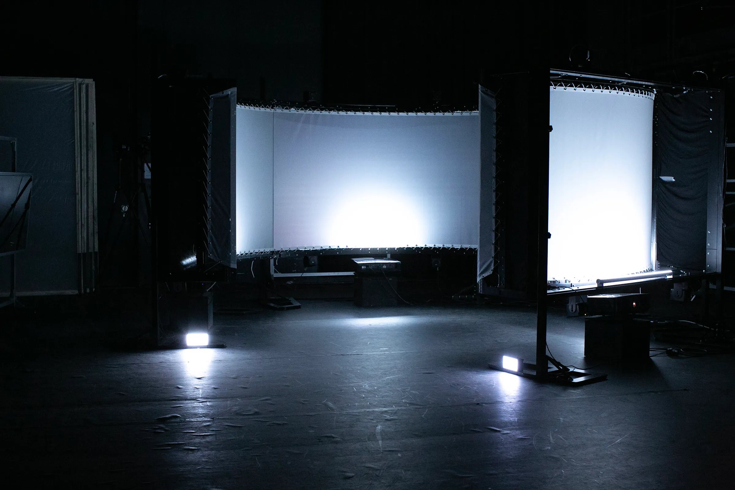 The empty installation: curved projection screens lit white in a dark hall