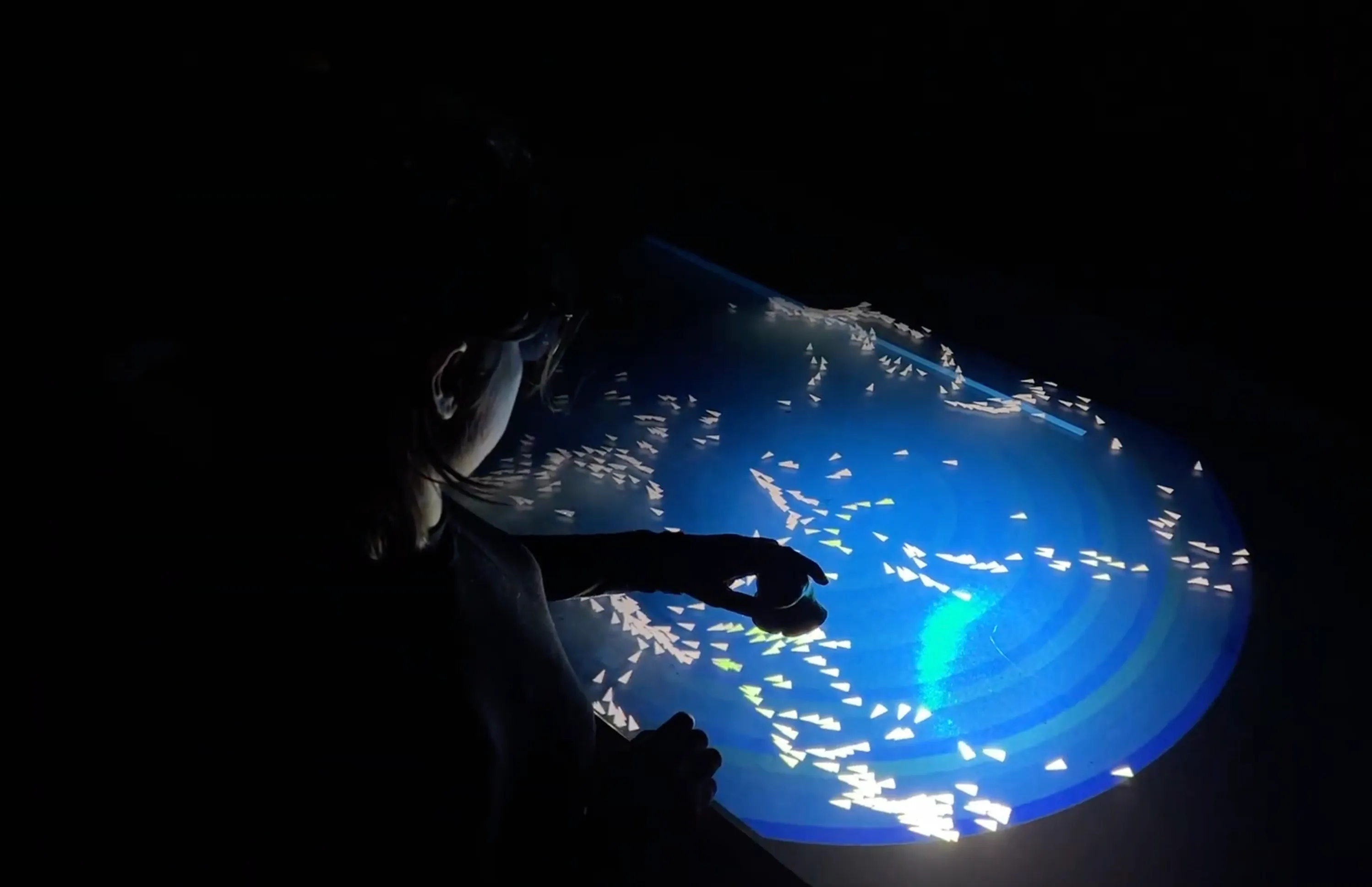 A player’s hand reaching into a swirl of blue light and particles on the table